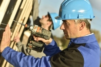 Construction worker using electric drill on building site (1)